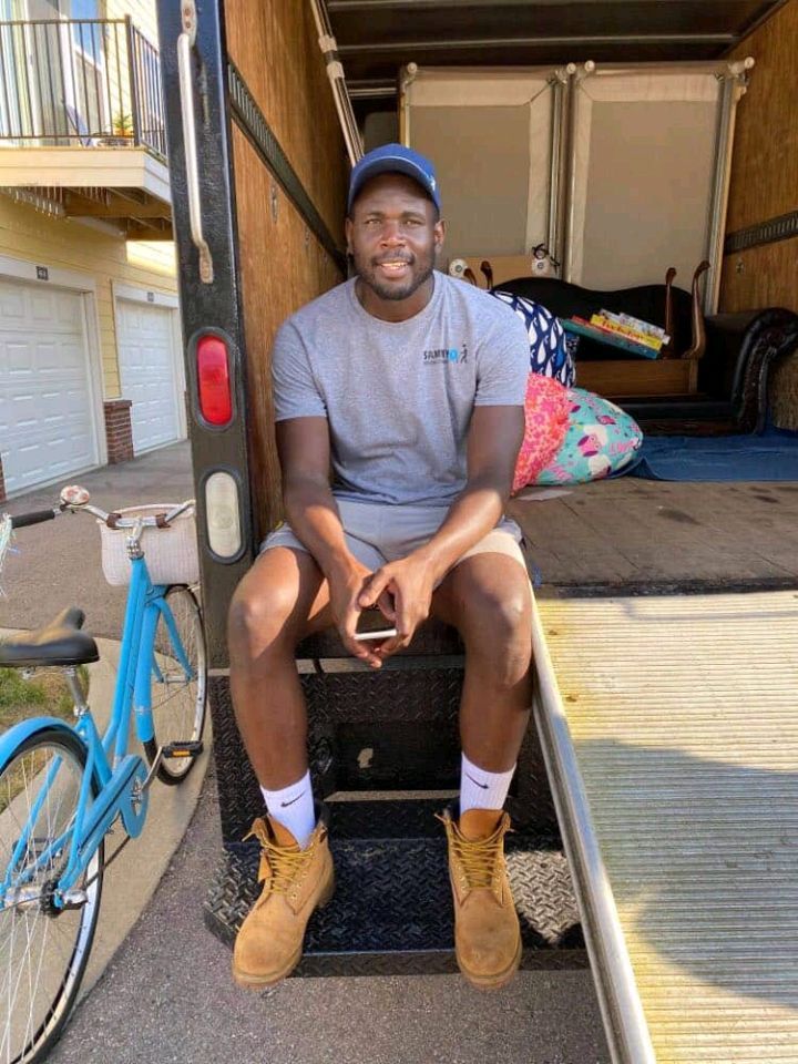 Sammy sitting on the truck ramp with a loaded truck behind him